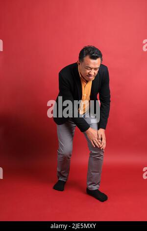 L'homme asiatique d'âge moyen debout sur fond rouge. Banque D'Images
