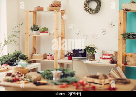 Intérieur d'un atelier moderne plein de décorations de Noël sur les espaces de travail : couronne de Noël sur le mur, guirlande d'étoiles suspendue entre les étagères avec boîte cadeau Banque D'Images