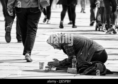 Une femme sans domicile mendiant sur ses genoux.Londres, Royaume-Uni. Banque D'Images