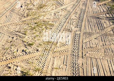 traces de voiture et empreintes de pas sur la surface de la route de campagne de sable en été après-midi Banque D'Images