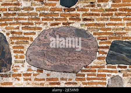 mur de briques en pierre d'un ancien bâtiment, partie d'un vieux mur en briques d'argile et de pierres de brebis polies Banque D'Images