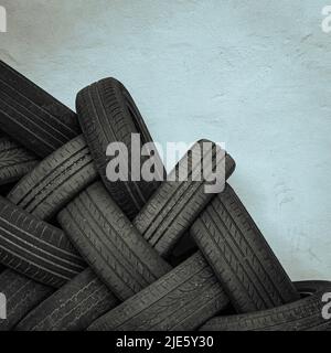 Image monochrome d'une pile de pneus de voiture entrelacés d'occasion contre un mur vierge prêt à être utilisé pour le vidage ou le recyclage Banque D'Images