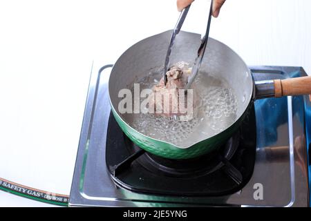 Femme bouillie du bœuf sur la poêle, sur la table blanche Banque D'Images