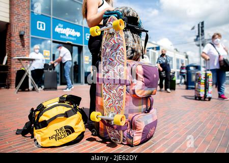 Norddeich, Allemagne. 25th juin 2022. Une jeune femme attend avec ses bagages et une longue planche qui lui est attachée dans le terminal de ferry dans le port pour le passage à l'île de Norderney. La Rhénanie-du-Nord-Westphalie est le premier État allemand à commencer ses vacances d'été. Credit: Hauke-Christian Dittrich/dpa/Alay Live News Banque D'Images