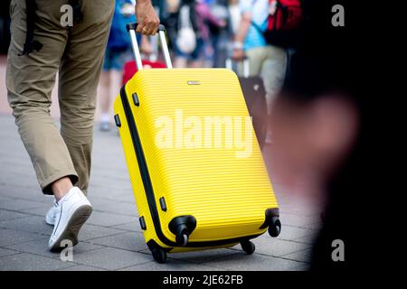 Norddeich, Allemagne. 25th juin 2022. Un homme marche jusqu'au terminal de ferry dans le port avec sa valise jaune pour se rendre à l'île de Norderney. La Rhénanie-du-Nord-Westphalie est le premier État allemand à commencer ses vacances d'été. Credit: Hauke-Christian Dittrich/dpa/Alay Live News Banque D'Images