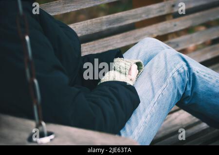 Petite fille assise sur un banc dans un parc d'automne. Banque D'Images