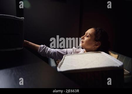 Portrait en gros plan d'une femme multitâches responsable des ventes, décoratrice d'intérieur qui organise des échantillons de matelas orthopédiques sur le stand dans la salle d'exposition de Banque D'Images