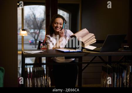 Charmante femme réussie, confiante directrice des ventes dans l'atelier de meubles, décoratrice d'intérieur debout au bureau et choisissant des nuances de tissu pour son pro Banque D'Images