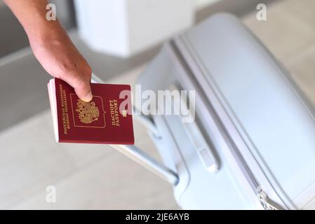 Une main tenant un passeport russe et une valise Banque D'Images