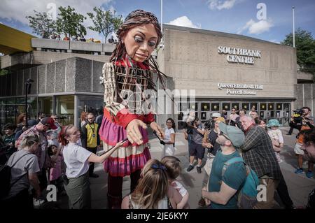 Londres, Royaume-Uni. 25th juin 2022. Little Amal revient en ville pour une brève présentation et représentation pour les enfants et les familles au centre Southbank. Amal, whoÕs nom signifie espoir en arabe, a voyagé de Turquie depuis juillet et a été créé par Handspring, la compagnie qui a fait les marionnettes équines dans War Horse. La marionnette de 3,5meter d’une jeune fille syrienne de neuf ans représente les millions d’enfants contraints de quitter leur foyer dans des situations désespérées. Credit: Guy Corbishley/Alamy Live News Banque D'Images