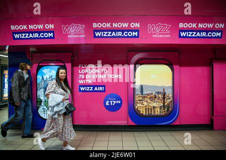 Les passagers ont passé la publicité Wizz Air affichée dans une station de métro. Banque D'Images