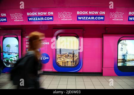 Une femme passe devant la publicité Wizz Air affichée dans une station de métro. Banque D'Images