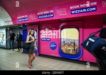 Les passagers ont passé la publicité Wizz Air affichée dans une station de métro. Banque D'Images