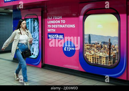 Une femme passe devant la publicité Wizz Air affichée dans une station de métro. Banque D'Images