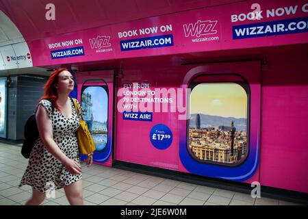 Une femme passe devant la publicité Wizz Air affichée dans une station de métro. Banque D'Images