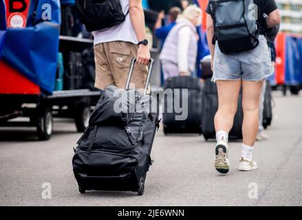 Norddeich, Allemagne. 25th juin 2022. Les touristes marchent avec leurs valises jusqu'au terminal de ferry dans le port pour se rendre à l'île de Juist. La Rhénanie-du-Nord-Westphalie est le premier État allemand à commencer ses vacances d'été. Credit: Hauke-Christian Dittrich/dpa/Alay Live News Banque D'Images