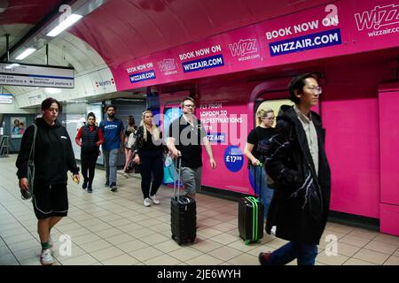 Londres, Royaume-Uni. 25th juin 2022. Les passagers avec des valises marchent devant la publicité Wizz Air affichée dans une station de métro. (Image de crédit : © Dinendra Haria/SOPA Images via ZUMA Press Wire) Banque D'Images