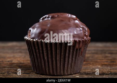 cupcake au chocolat dans un emballage en papier noir, cupcake au chocolat avec saveur de chocolat sur une table en bois Banque D'Images