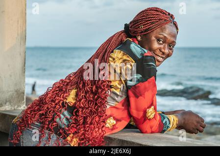 Femme africaine avec de beaux cheveux rasta rouges surplombant la mer depuis un balcon à Accra Ghana Afrique de l'Ouest Banque D'Images