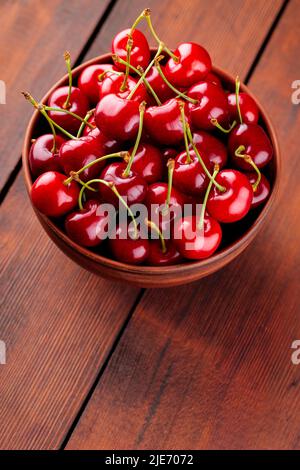 Cerises mûres dans un bol en argile. Cerises rouges sur une table en bois. Concept alimentaire végétalien sain. Vue de dessus. Copier l'espace Banque D'Images