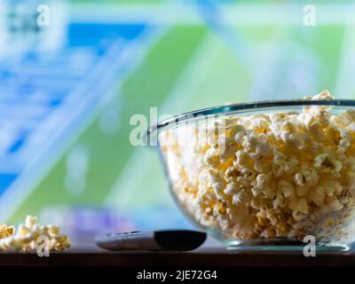 Gros plan. Un grand bol de pop-corn et une télécommande pour téléviseur sur fond de rêve. Détendez-vous dans le confort de la maison devant le téléviseur, en regardant votre favo Banque D'Images