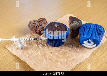 Seringue injectant de l'insuline dans la vue Muddy Chocolate muffin Side. Banque D'Images