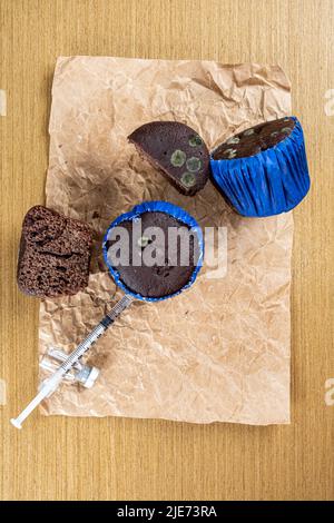 Seringue injectant de l'insuline dans un muffin au chocolat moulant top View vertical. Banque D'Images