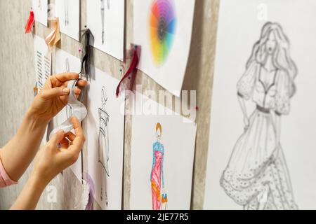 Le designer de mode développe des croquis de la conception de vêtements. L'artiste crée des robes pour femmes. Travailler sur mesure avec le tissu. Banque D'Images