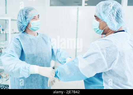 Inspire l'infirmière à aider sa collègue à porter un uniforme Banque D'Images