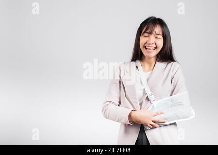 Bras cassé. Femme d'affaires confiante souriante bras cassé après accident et porter une attelle de bras pour le traitement, excitée happy Asian soutien de harnais femelle han Banque D'Images