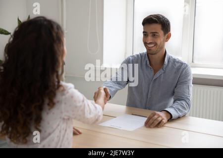 Un homme d'affaires hispanique se secoue les mains d'une candidate lors d'une entrevue d'emploi réussie Banque D'Images