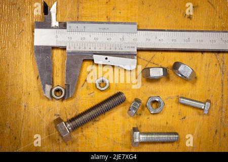 jeu de vis de différentes tailles mesurées par un pied à coulisse sur un ancien établi en bois Banque D'Images