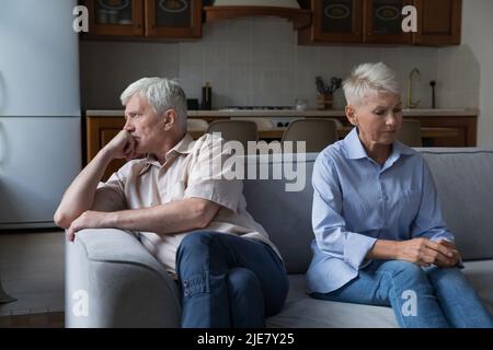 Un couple plus âgé sérieux de querelles s'assoit séparément sur le lit Banque D'Images