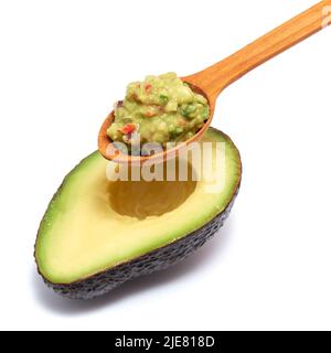 Cuillère en bois de sauce à trempette guacamole et moitié d'avocat isolée sur fond blanc Banque D'Images