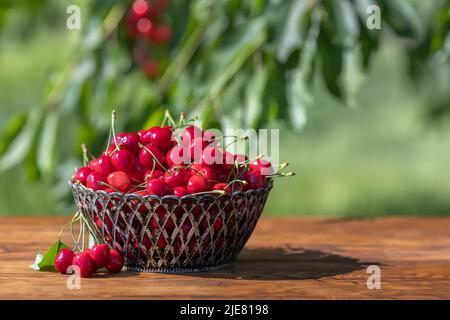 cerises mûres dans un panier sur une table en bois à l'extérieur Banque D'Images