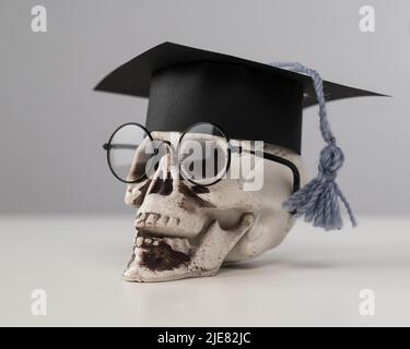 Crâne en plastique avec bonnet et lunettes universitaires. Banque D'Images