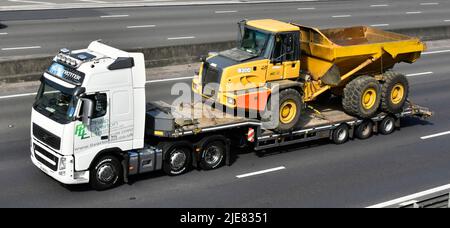 Entreprise de transport conduite de camions hgv et remorque à chargeur bas transportant un camion benne basculante articulée Bell B300 jaune sur l'autoroute britannique Banque D'Images