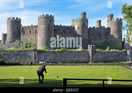 Vue sur le château de Conwy de l'historique Grade I classé toile de fond de bâtiment pour homme plus âgé pratiquant des compétences de boules sur l'herbe impeccable vert de bowling Gwynedd Royaume-Uni Banque D'Images