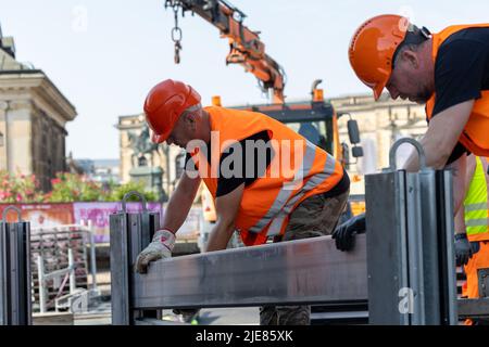 Dresde, Allemagne. 26th juin 2022. Deux employés du Regiebetrieb Zentrale Technische Dienstleistungen (RB ZTDL) de la ville placent un élément de protection contre les inondations dans l'appareil. Lors de l'installation d'essai du système de protection mobile contre les inondations dans le centre-ville de Dresde, des travaux d'entretien sont effectués sur le système, les éléments sont nettoyés et leur fonctionnalité testée. Credit: Daniel Schäfer/dpa/Alay Live News Banque D'Images