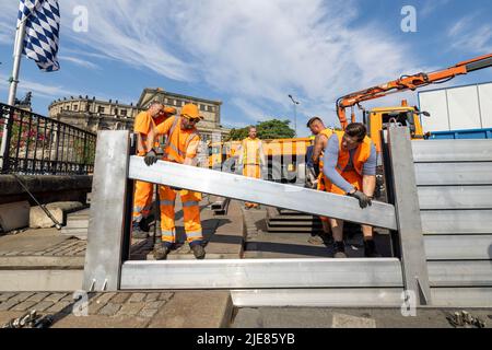 Dresde, Allemagne. 26th juin 2022. Deux employés du Regiebetrieb Zentrale Technische Dienstleistungen (RB ZTDL) de la ville placent un élément de protection contre les inondations dans l'appareil. Lors de l'installation d'essai du système de protection mobile contre les inondations dans le centre-ville de Dresde, des travaux d'entretien sont effectués sur le système, les éléments sont nettoyés et leur fonctionnalité testée. Credit: Daniel Schäfer/dpa/Alay Live News Banque D'Images