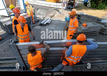 Dresde, Allemagne. 26th juin 2022. Deux employés du Regiebetrieb Zentrale Technische Dienstleistungen (RB ZTDL) de la ville installent un élément de protection contre les inondations dans l'appareil. Lors de l'installation d'essai du système de protection mobile contre les inondations dans le centre-ville de Dresde, des travaux d'entretien sont effectués sur le système, les éléments sont nettoyés et leur fonctionnalité testée. Credit: Daniel Schäfer/dpa/Alay Live News Banque D'Images