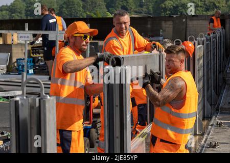 Dresde, Allemagne. 26th juin 2022. Trois employés du Regiebetrieb Zentrale Technische Dienstleistungen (RB ZTDL) de la ville installent un élément de protection contre les inondations dans l'appareil. Lors de l'installation d'essai du système de protection mobile contre les inondations dans le centre-ville de Dresde, des travaux d'entretien sont effectués sur le système, les éléments sont nettoyés et leur fonctionnalité testée. Credit: Daniel Schäfer/dpa/Alay Live News Banque D'Images