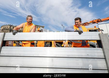 Dresde, Allemagne. 26th juin 2022. Deux employés du Regiebetrieb Zentrale Technische Dienstleistungen (RB ZTDL) de la ville installent un élément de protection contre les inondations dans l'appareil. Lors de l'installation d'essai du système de protection mobile contre les inondations dans le centre-ville de Dresde, des travaux d'entretien sont effectués sur le système, les éléments sont nettoyés et leur fonctionnalité testée. Credit: Daniel Schäfer/dpa/Alay Live News Banque D'Images