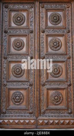 Anciennes portes en bois massif ornées de décorations sculptées à la main par des artistes locaux, dans le splendide centre historique de Lucques Banque D'Images