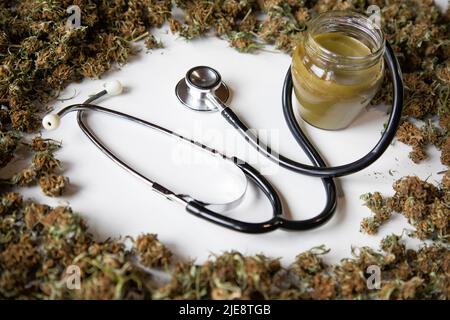 concept de marijuana médicale, bourgeons de marijuana dans un cercle, onguent de marijuana et stéthoscope à l'intérieur. fond blanc Banque D'Images