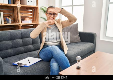 Jeune femme travaillant au bureau de consultation souriant gai jouant un coup de pied avec les mains montrant le visage. Surpris et sorti Banque D'Images