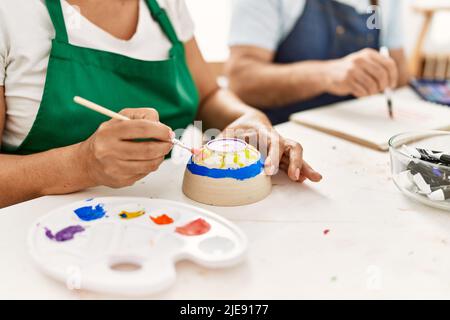 Peintre hispanique d'âge moyen peint en couple dans un studio d'art. Banque D'Images