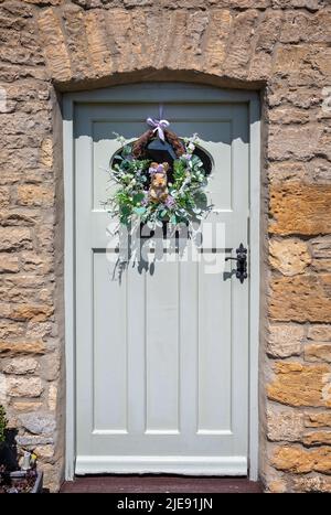 Guirlande charmante avec écureuil de paille entourée de graminées et de fleurs accrochées à la porte d'entrée rustique Banque D'Images