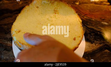 un chef pâtissier met un gâteau sur une crème à la cerise et le presse. Aplatit et aplatit le gâteau en gros plan. Banque D'Images