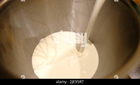 Fouetter les blancs de crème dans le robot ménager. Mains de chef professionnel de sexe masculin ajoutant de la crème au bol de cuisine moderne en argent batteur sur socle. Banque D'Images